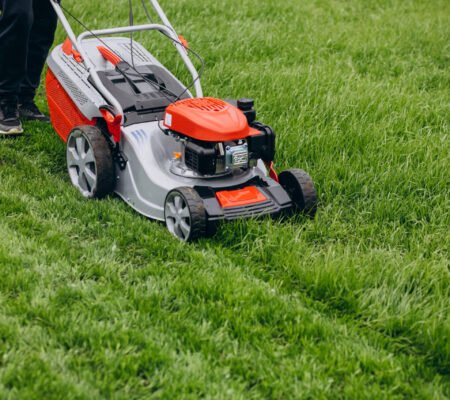 Man cutting grass with lawn mover in the back yard